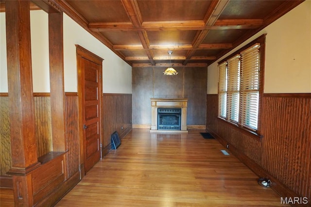 130 E 2nd St, Hermann, MO 65041 - unfurnished living room with light wood-type flooring, wood walls, a glass covered fireplace, wainscoting, and coffered ceiling