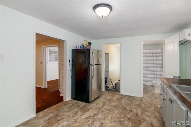 601 E Jefferson St, Ofallon, IL 62269 - kitchen with freestanding refrigerator, white cabinetry, a textured ceiling, and dark countertops