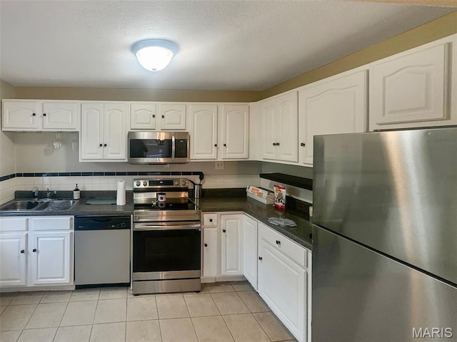 2806 Mohattan Ln, Saint Louis, MO 63125 - kitchen with appliances with stainless steel finishes, dark countertops, white cabinets, and light tile patterned floors