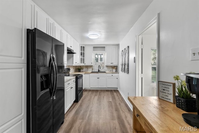 911 Cordova St, Saint Ferdinand Township, MO 63138 - kitchen featuring black appliances, under cabinet range hood, light wood-type flooring, white cabinetry, and tasteful backsplash