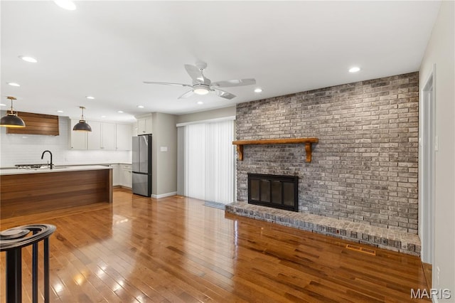 502 Lalor Dr, Manchester, MO 63011 - unfurnished living room with ceiling fan, recessed lighting, a brick fireplace, and light wood-type flooring