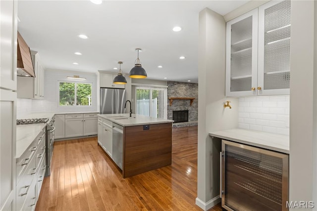 502 Lalor Dr, Manchester, MO 63011 - kitchen with beverage cooler, appliances with stainless steel finishes, tasteful backsplash, a fireplace, and light wood-style flooring
