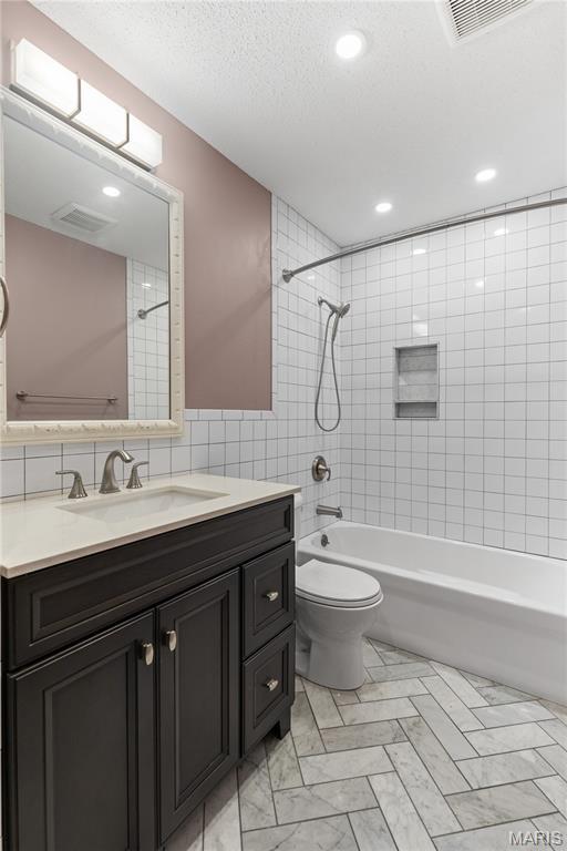 502 Lalor Dr, Manchester, MO 63011 - bathroom featuring tile walls, vanity, washtub / shower combination, recessed lighting, and a textured ceiling