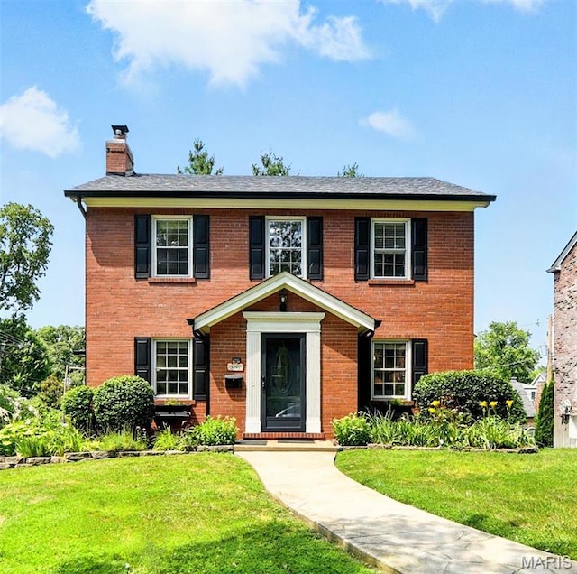 8049 Gannon Ave, Saint Louis, MO 63130 - view of front facade featuring a chimney, brick siding, and a front lawn