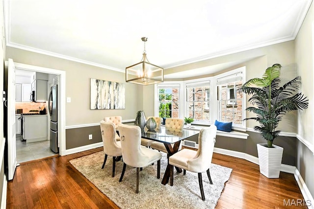 8049 Gannon Ave, Saint Louis, MO 63130 - dining room featuring crown molding, wood-type flooring, and a chandelier