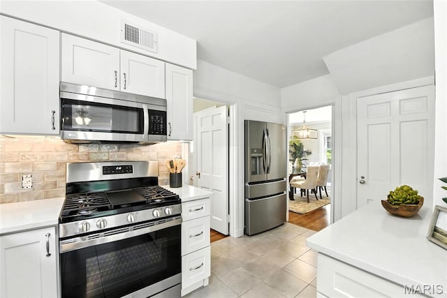 8049 Gannon Ave, Saint Louis, MO 63130 - kitchen with appliances with stainless steel finishes, light countertops, decorative backsplash, and white cabinets
