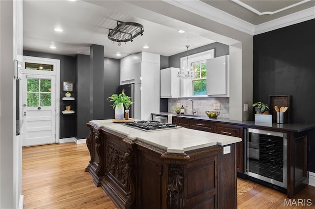 316 Melville Ave, University City, MO 63130 - kitchen featuring beverage cooler, appliances with stainless steel finishes, white cabinets, light wood-style floors, and dark brown cabinetry