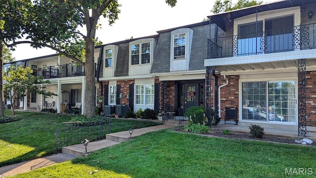 1669 Mayenne Ct Unit B, Mehlville, MO 63125 - view of front of property featuring mansard roof, brick siding, a balcony, a front lawn, and roof with shingles