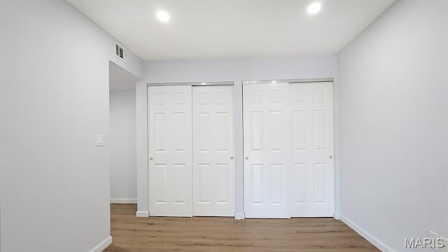 1669 Mayenne Ct Unit B, Mehlville, MO 63125 - unfurnished bedroom featuring two closets, wood finished floors, and recessed lighting