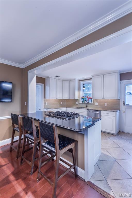 220 Orrick Ln, Kirkwood, MO 63122 - kitchen featuring tasteful backsplash, white cabinetry, crown molding, a breakfast bar, and appliances with stainless steel finishes