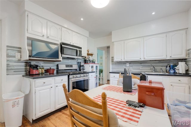 1485 E Duchesne Dr, Florissant, MO 63031 - kitchen with appliances with stainless steel finishes, tasteful backsplash, white cabinets, and dark countertops