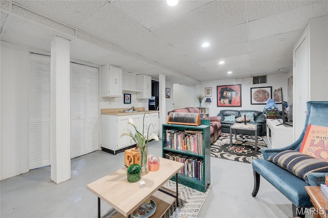 1485 E Duchesne Dr, Florissant, MO 63031 - living room featuring finished concrete flooring, a drop ceiling, and recessed lighting