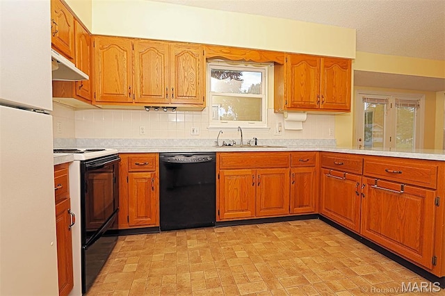 643 Woodgate St, Farmington, MO 63640 - kitchen with black appliances, under cabinet range hood, light countertops, brown cabinetry, and backsplash