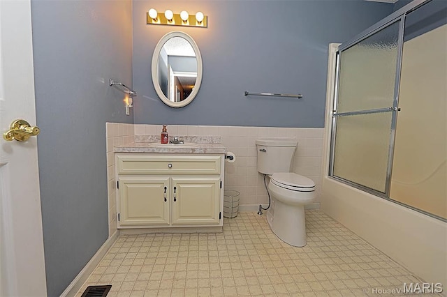 643 Woodgate St, Farmington, MO 63640 - full bathroom with vanity, shower / bath combination with glass door, a wainscoted wall, tile walls, and tile patterned floors