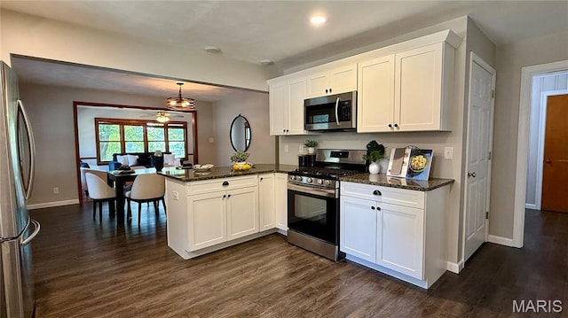 504 N Moore St, Waterloo, IL 62298 - kitchen featuring stainless steel appliances, a peninsula, dark wood-style flooring, white cabinets, and dark stone countertops