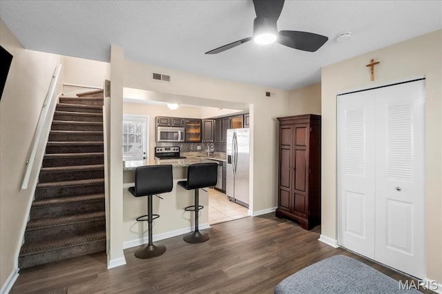 9053 W Swan Cir, Brentwood, MO 63144 - kitchen with appliances with stainless steel finishes, a kitchen bar, wood finished floors, and ceiling fan
