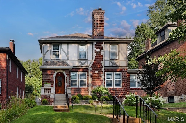 728 Yale Ave, Saint Louis, MO 63130 - tudor-style house with stucco siding, brick siding, a front lawn, entry steps, and a chimney
