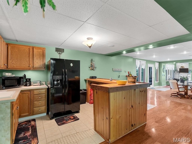 394 Sunset Echo Rd, Union, MO 63084 - kitchen with black appliances, a drop ceiling, a center island, light countertops, and light wood-type flooring