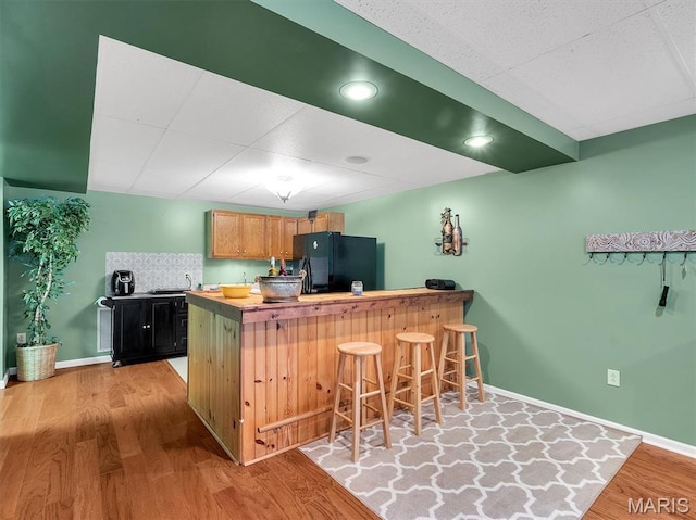 394 Sunset Echo Rd, Union, MO 63084 - kitchen with freestanding refrigerator, a peninsula, light wood-type flooring, a breakfast bar, and a paneled ceiling