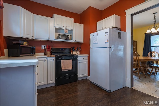 2324 Grand Ave, Granite City, IL 62040 - kitchen with freestanding refrigerator, black range with gas cooktop, stainless steel microwave, dark wood-style floors, and white cabinetry