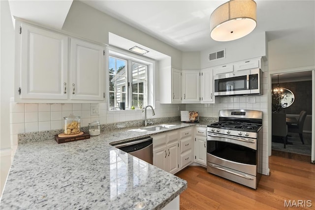 43 Highgate Rd, Olivette, MO 63132 - kitchen with appliances with stainless steel finishes, light stone countertops, light wood finished floors, and white cabinets