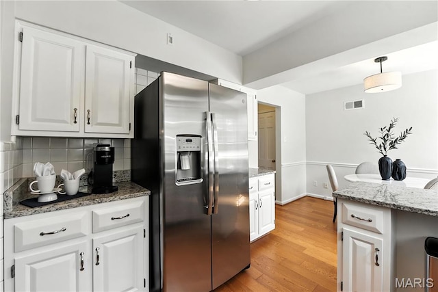 43 Highgate Rd, Olivette, MO 63132 - kitchen with stainless steel refrigerator with ice dispenser, decorative backsplash, white cabinets, light stone counters, and light wood-style floors