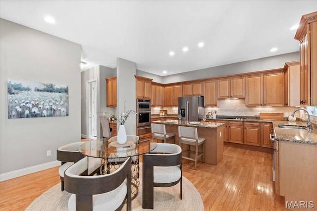 1931 Chesterfield Ridge Cir, Chesterfield, MO 63017 - kitchen with stainless steel appliances, a center island, light wood-style floors, stone countertops, and a breakfast bar area