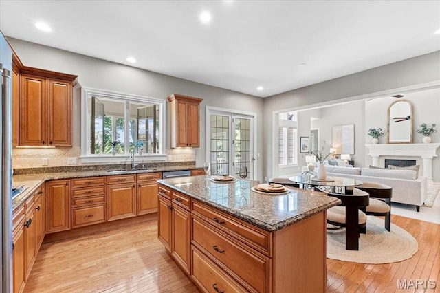 1931 Chesterfield Ridge Cir, Chesterfield, MO 63017 - kitchen featuring light wood finished floors, a center island, decorative backsplash, dark stone countertops, and stainless steel dishwasher
