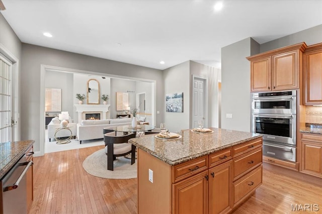 1931 Chesterfield Ridge Cir, Chesterfield, MO 63017 - kitchen featuring a warming drawer, appliances with stainless steel finishes, light wood-type flooring, a glass covered fireplace, and recessed lighting