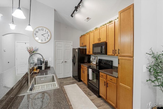 27 Kassebaum Ln Unit 302, Mehlville, MO 63129 - kitchen with black appliances, dark countertops, track lighting, light wood finished floors, and decorative light fixtures