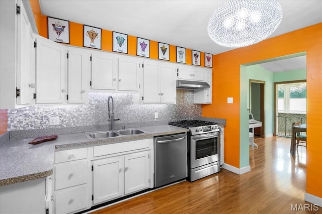 1239 Vero Ln, Ellisville, MO 63011 - kitchen with stainless steel appliances, white cabinetry, wood finished floors, backsplash, and under cabinet range hood