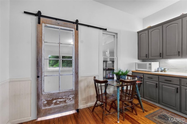 713 W Adams St, Jackson, MO 63755 - dining area featuring a barn door, light wood-style floors, wainscoting, and wood walls