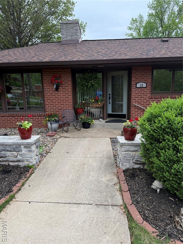 15 Lake Pembroke Dr, Ferguson, MO 63135 - doorway to property featuring brick siding, a chimney, covered porch, and a shingled roof