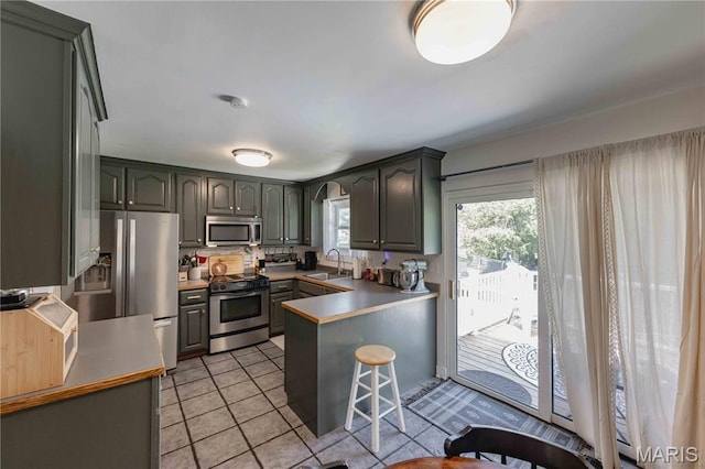 3712 Gail Dr, Imperial, MO 63052 - kitchen featuring stainless steel appliances, a peninsula, light tile patterned floors, a breakfast bar area, and arched walkways
