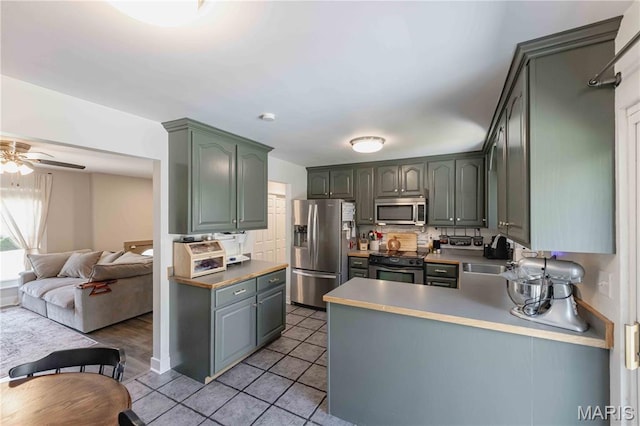 3712 Gail Dr, Imperial, MO 63052 - kitchen featuring appliances with stainless steel finishes, open floor plan, a peninsula, light tile patterned floors, and backsplash