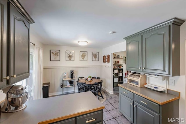 3712 Gail Dr, Imperial, MO 63052 - kitchen with light tile patterned floors, a wainscoted wall, a peninsula, and dark countertops