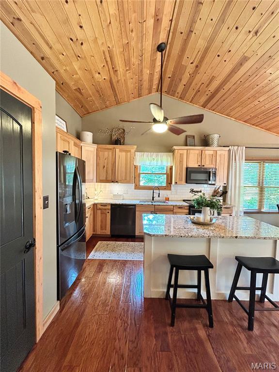 5156 Mccallister Rd, Gerald, MO 63037 - kitchen with black fridge, dishwashing machine, stainless steel microwave, light brown cabinetry, and lofted ceiling