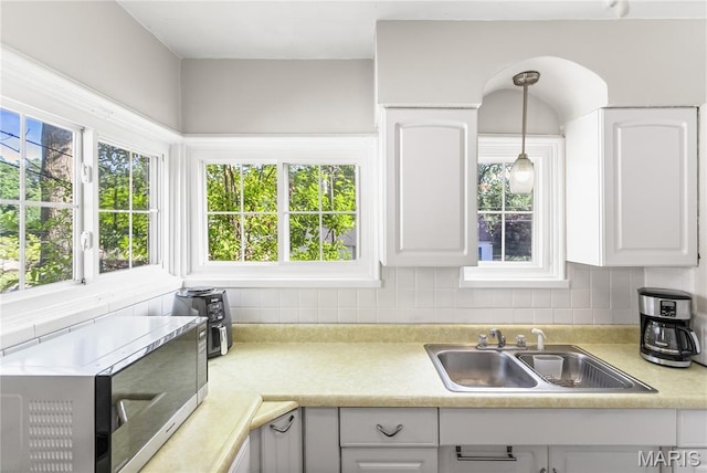 1106 Danforth St, Alton, IL 62002 - kitchen featuring stainless steel microwave, light countertops, tasteful backsplash, and white cabinetry