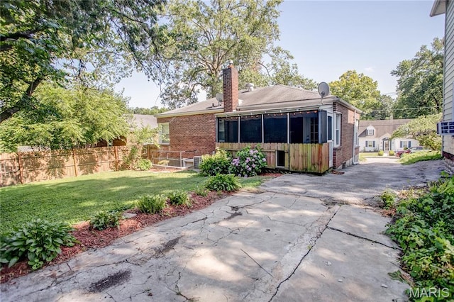 1106 Danforth St, Alton, IL 62002 - rear view of house featuring a chimney, brick siding, a sunroom, and a patio