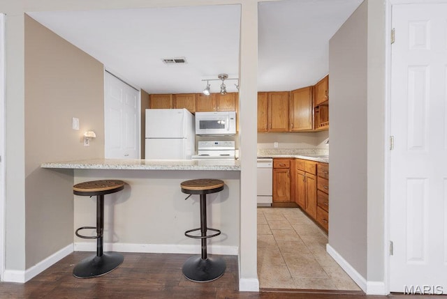 4 Fairways Cir Unit I, Saint Charles, MO 63303 - kitchen featuring white appliances, brown cabinets, a kitchen bar, and a peninsula
