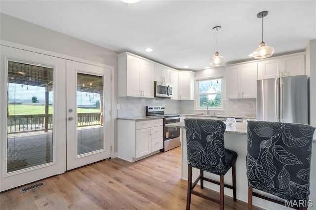 904 Ampere Pl, Lake St Louis, MO 63367 - kitchen with stainless steel appliances, french doors, a breakfast bar, white cabinets, and recessed lighting