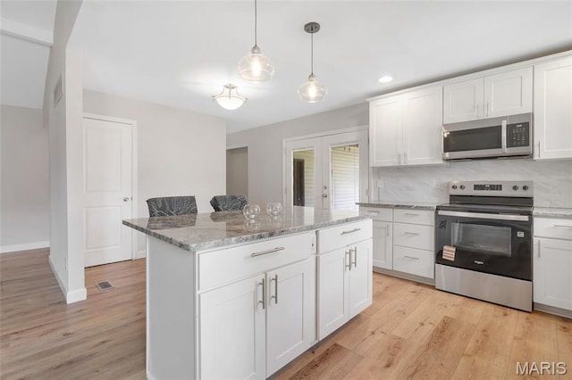 904 Ampere Pl, Lake St Louis, MO 63367 - kitchen featuring stainless steel appliances, light wood finished floors, a kitchen island, white cabinets, and pendant lighting