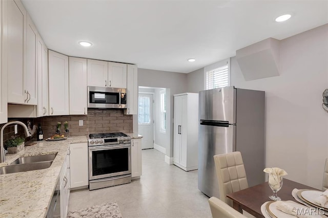 3253 Walter Ave, Maplewood, MO 63143 - kitchen with stainless steel appliances, decorative backsplash, white cabinetry, recessed lighting, and light stone counters