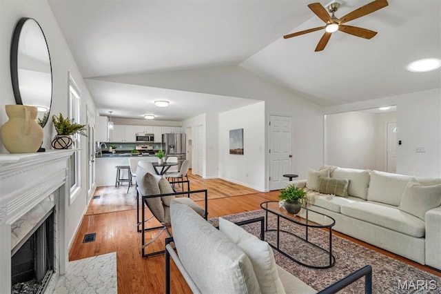3848 Bedford Pointe Dr, Wentzville, MO 63385 - living area with a ceiling fan, vaulted ceiling, a premium fireplace, and light wood-style flooring