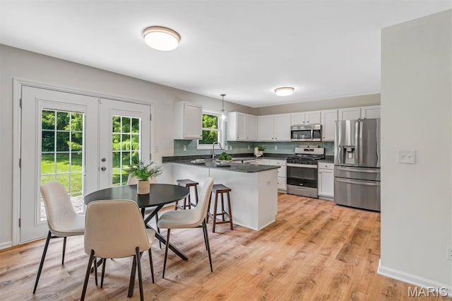 3848 Bedford Pointe Dr, Wentzville, MO 63385 - kitchen with stainless steel appliances, a peninsula, french doors, white cabinetry, and light wood finished floors