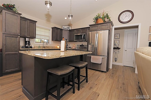 3576 Mill View Xing, Cape Girardeau, MO 63701 - kitchen with appliances with stainless steel finishes, vaulted ceiling, dark brown cabinets, light stone counters, and a center island