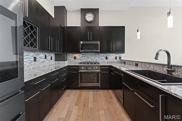 8025 Maryland Ave Unit 8H, Clayton, MO 63105 - kitchen featuring appliances with stainless steel finishes, light wood-style floors, hanging light fixtures, and light stone counters