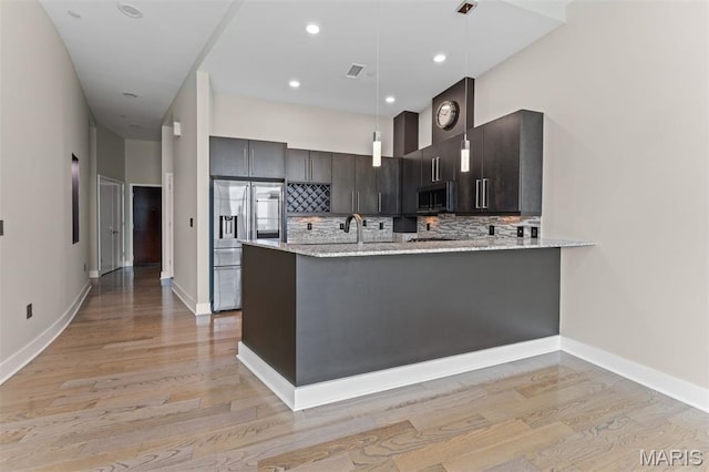 8025 Maryland Ave Unit 8H, Clayton, MO 63105 - kitchen with stainless steel appliances, light wood-style flooring, a peninsula, light stone counters, and recessed lighting