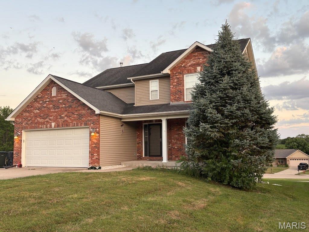 168 Juliana Ct, Columbia, IL 62236 - traditional home with brick siding, a front lawn, a garage, driveway, and covered porch