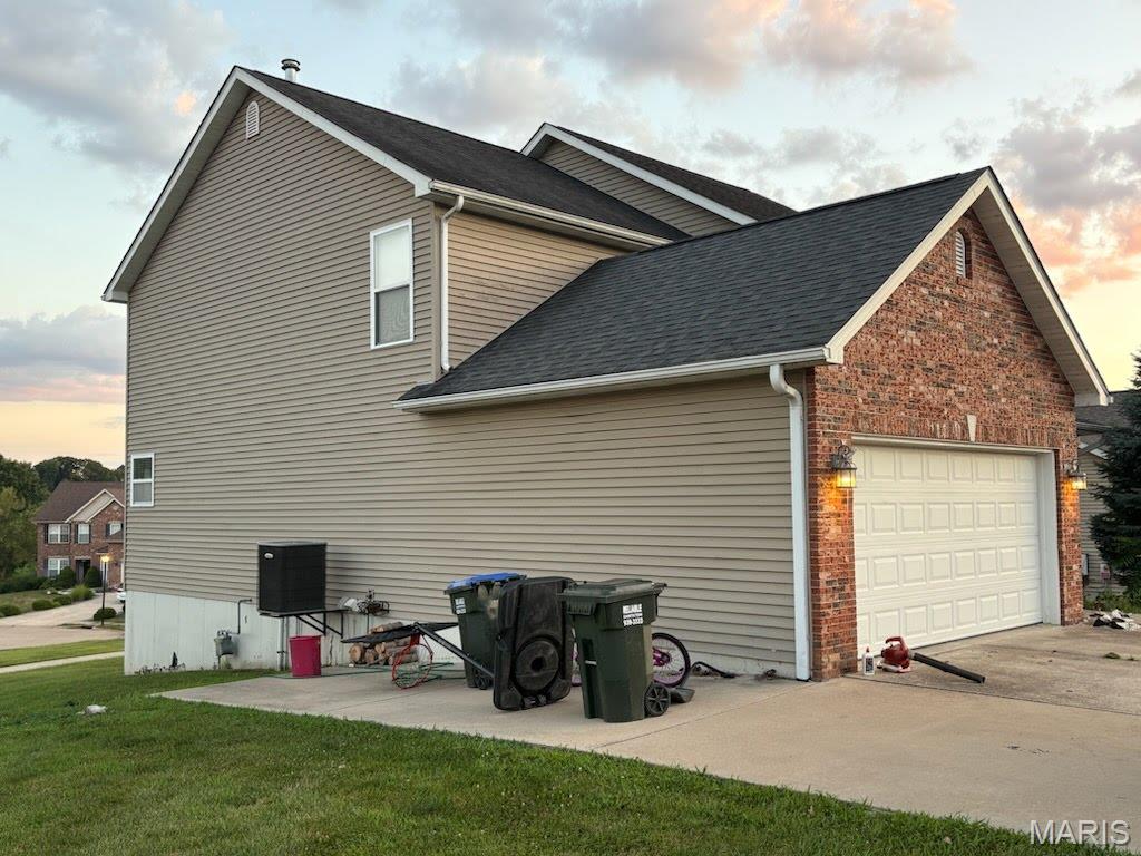 168 Juliana Ct, Columbia, IL 62236 - property exterior at dusk with an attached garage, concrete driveway, a yard, and a shingled roof